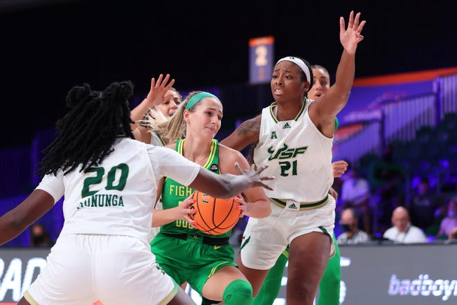 In this photo provided by Bahamas Visual Services, Oregon guard Maddie Scherr, center, drives against South Florida forward Bethy Mununga (20) and center Shae Leverett (21) during an NCAA college basketball game at Paradise Island, Bahamas, Monday, Nov. 22, 2021.