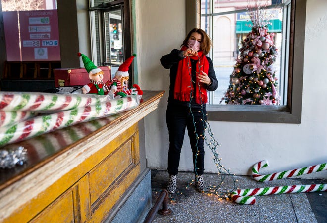 Melissa Hansen Schmadeke, executive director of the Springfield Memorial Foundation, prepares a string of lights as she decorates the store front of the former VELE restaurant location on Sixth Street for the Memorial Holiday Fest in Springfield, Ill., Monday, November 22, 2021. The Memorial Holiday Fest will open Nov. 27th and will continue on Saturdays and Wednesday evenings until Dec. 22nd in downtown Springfield. [Justin L. Fowler/The State Journal-Register]