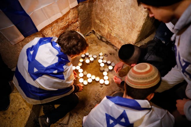 Pemuda Israel menyalakan lilin berbentuk Bintang Daud di lokasi serangan penembakan yang menewaskan seorang pria Israel di Kota Tua Yerusalem, Minggu, 21 November 2021.