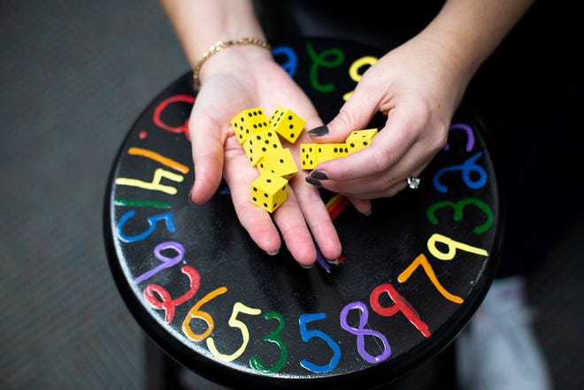 A teacher holds a set of dice she uses to teach math to her students.