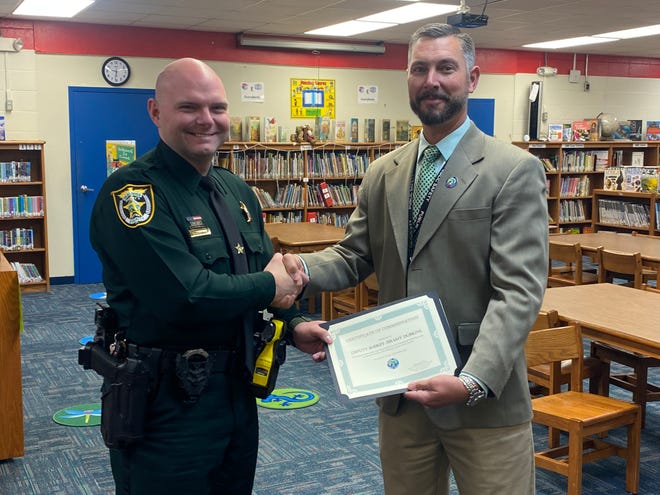 Okaloosa County Sheriff's Office School Resource Officer Deputy Jeramy Dobkins shakes hands with Okaloosa County School District Safe Schools Specialist Danny Dean after receiving a Certificate of Commendation. Dobkins was recognized for his "profound innovation" in creating a QR code that helps students discretely access Fortify Florida, an anonymous reporting tool.
