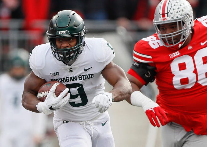 Michigan State running back Kenneth Walker III runs past Ohio State Buckeyes defensive tackle Jerron Cage during the first quarter at Ohio Stadium in Columbus, Ohio on Nov. 20, 2021.
