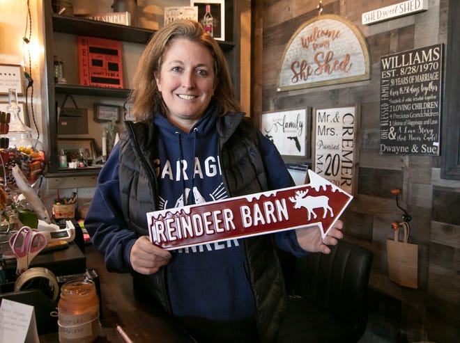 Kristy Ellis, owner of That's What She Shed Boutique, holds one of a number of signs specific to the holidays in her Hartland store Tuesday, Nov. 23, 2012.