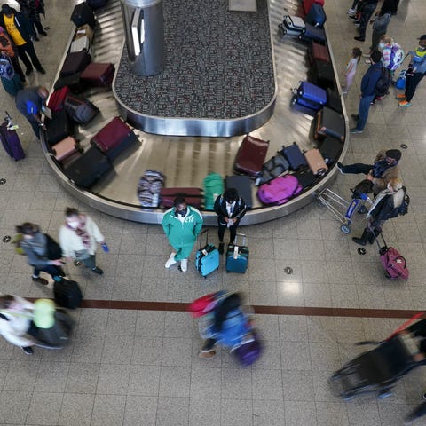 Travelers wait for their luggage to arrive in bagg