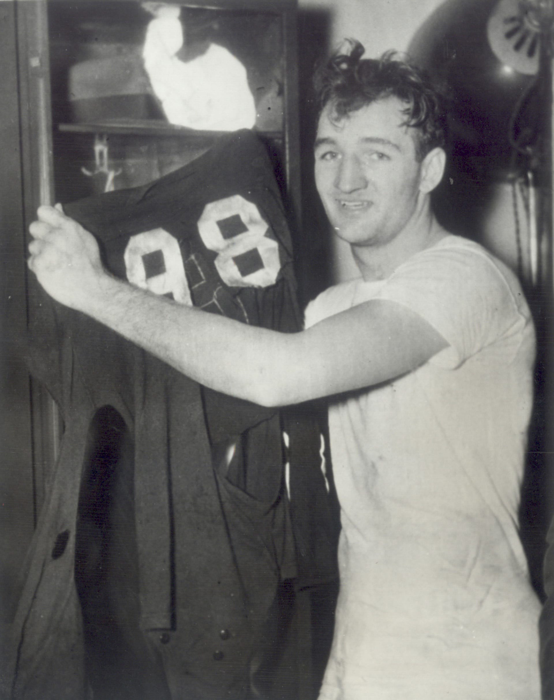 COLUMBUS, OHIO--Tom Harmon hands up his No. 98 jersey after scoring three touchdowns in Michigan's smashing, 40-0, victory over Ohio State at Columbus.  Harmon boosted his three-year touchdown total to 33, surpassing the 15-year-old mark of Illinois' immortal Red Grange, who tallied 31.  The tattered jersey typifies Harmon's smashing play, which often caused him to have two jerseys town off during a game.