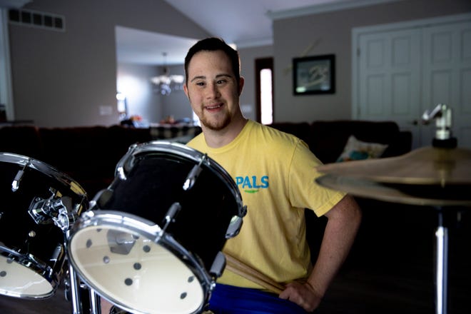 Austin Brown, 23, sits at his drum set in his home on Monday, Nov. 22, 2021 at his residents in Bridgetown. Brown, a person who has Down syndrome, graduated from the Pathways to Employment program through the Hamilton County Educational Service Center in 2020. Brown is currently employed by McAlister's Deli and plays the drums and guitar.