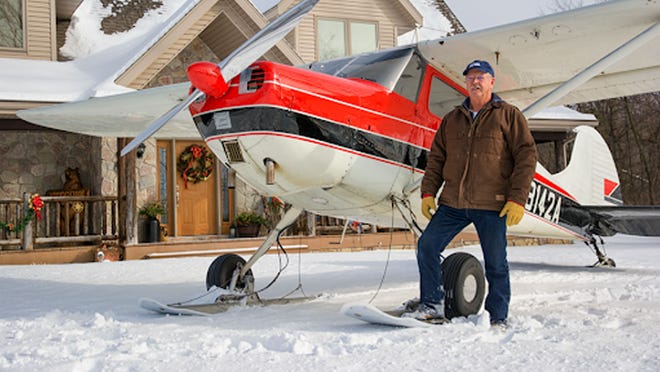 Don Kiel stands next to a small airplane with snow skis.