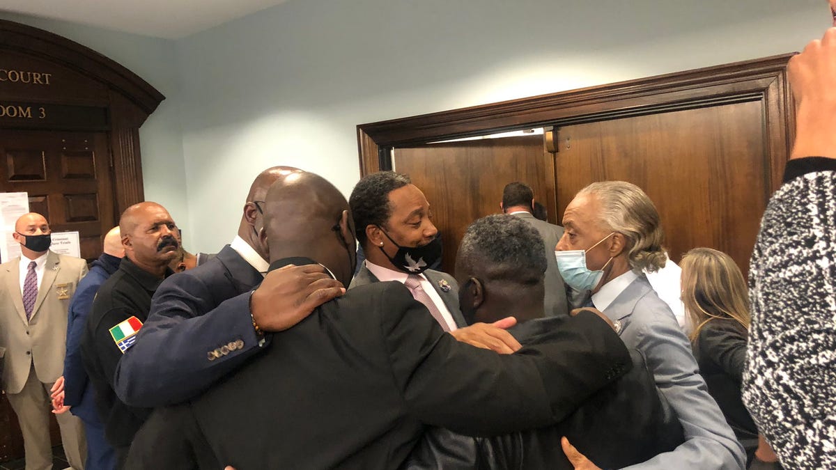 Arbery's father, Marcus, embraces Ben Crump and Rev. Al Sharpton outside the courtroom.