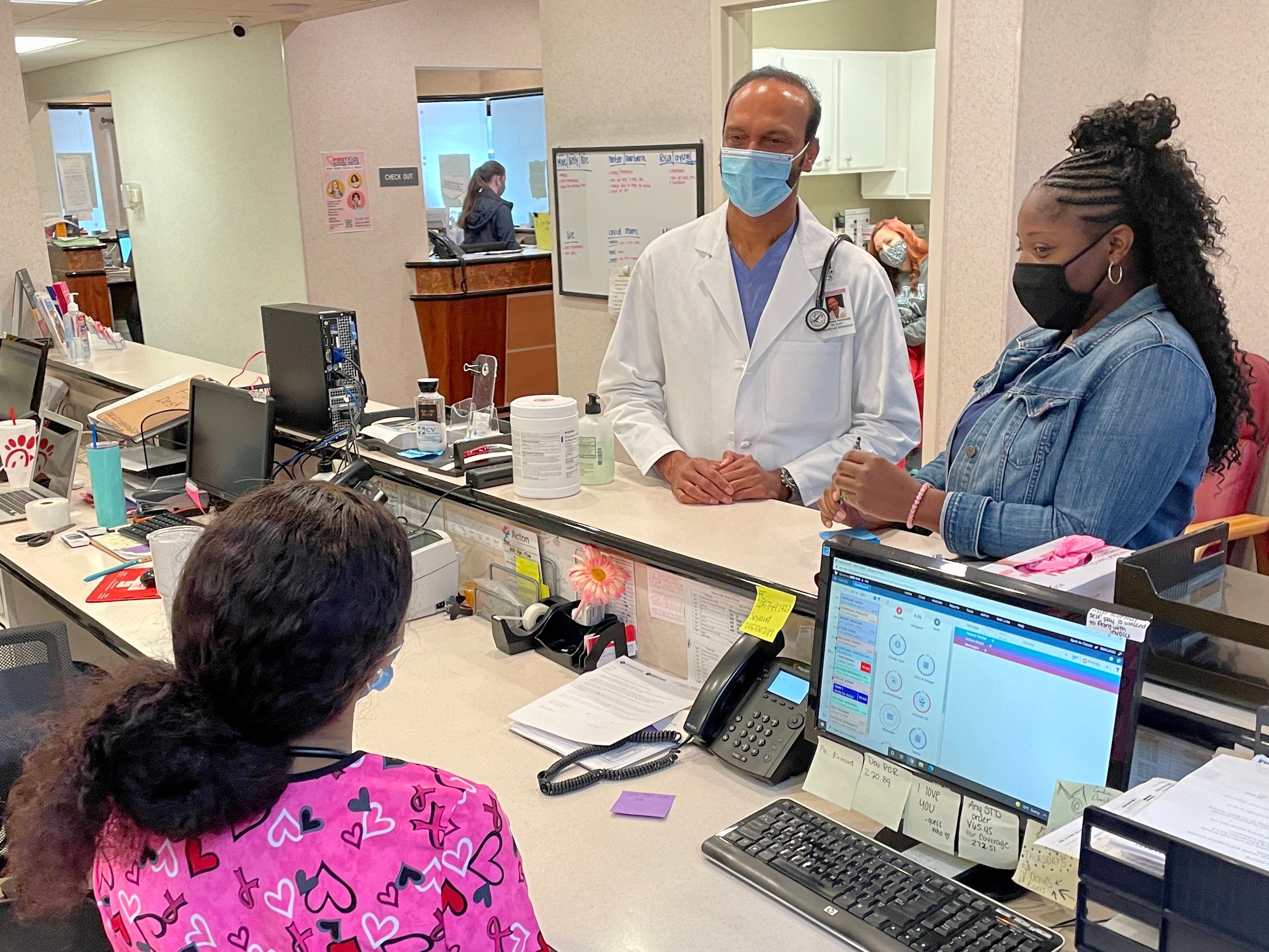 Dr. Ramesh Peramsetty, center, speaks with medical assistants Crystal Cain, standing, and Breanna Wilkins between patients at his Crimson Care clinic on Veterans Memorial Parkway in Tuscaloosa.