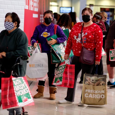 Black Friday shoppers wearing face masks wait in l
