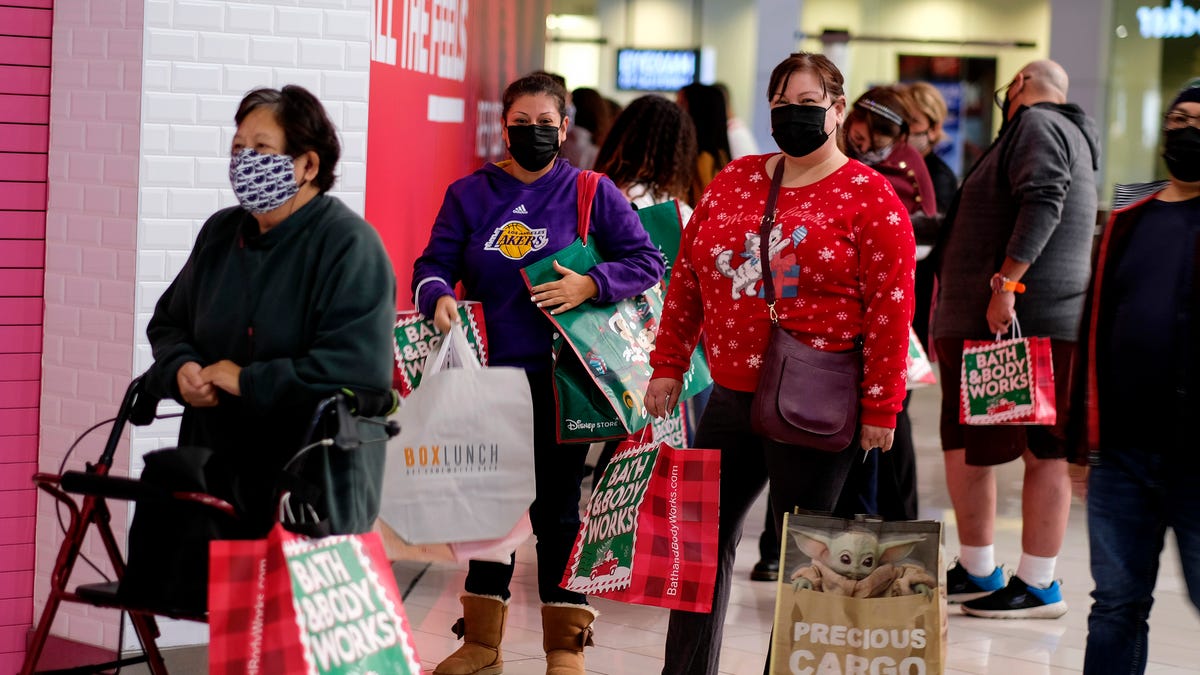 Black Friday shoppers wearing face masks wait in line to enter a store at the Glendale Galleria in Glendale, Calif., Friday, Nov. 27, 2020.