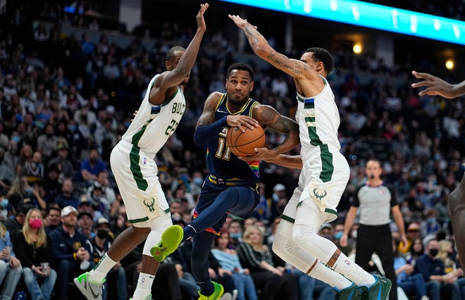 The Bucks' Khris Middleton, left, and George Hill converge as Nuggets guard Monte Morris drives to the basket Friday night in Denver