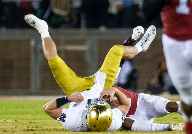 Stanford's Kendall Williamson (21) takes down Notre Dame’s Jack Coan (17) during the Notre Dame vs. Stanford NCAA football game Saturday, Nov. 27, 2021 at Stanford Stadium in Palo Alto, Calif. 