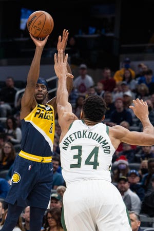 Nov 28, 2021; Indianapolis, Indiana, USA; Indiana Pacers forward Justin Holiday (8) shoots the ball while Milwaukee Bucks forward Giannis Antetokounmpo (34) defends  in the first quarter at Gainbridge Fieldhouse.