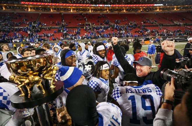 Head coach Mark Stoops exults as his players hold the Governor's Cup trophy after the Wildcats rolled past Louisville 52-21 Saturday night.  Nov.  27, 2021 