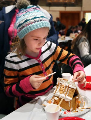 Karie Graham, 6, carefully places items on her gingerbread house roof Saturday  morning in Memorial Hall during the 2019 Gingerbread House Decorating event. 