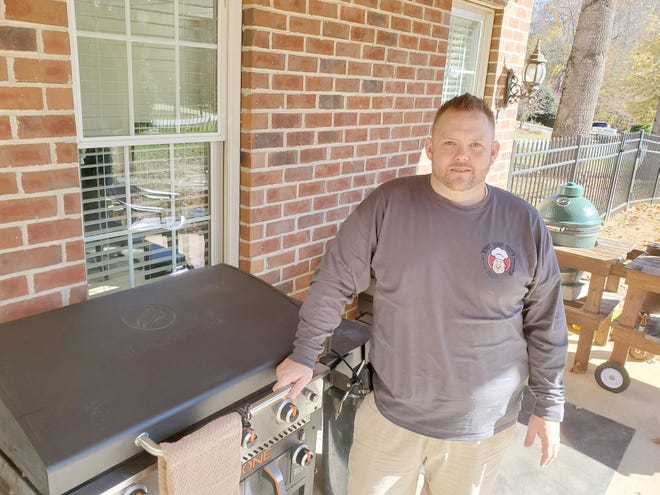 Matthew Hussey, aka The Hungry Hussey, stands next to one of two Blackstone grills he owns and two Big Green Egg smokers and grills on his back porch in Trinity. He uses them and a pellet grill to demonstrate and serve up new recipes videos to his 118,000 subscribers on his Hungry Hussey YouTube channel.