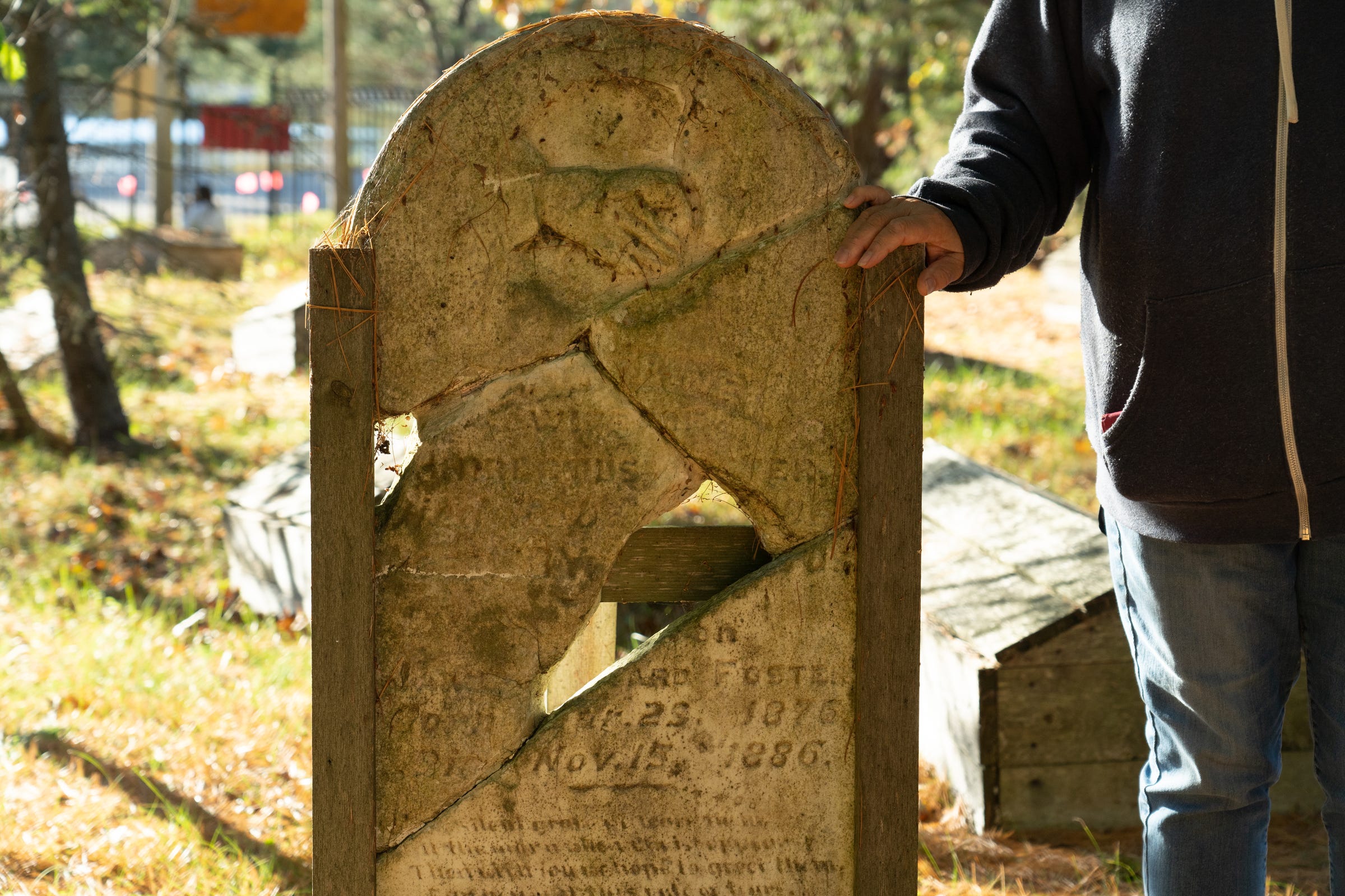 Wanda Perron, 73, of Bay Mills Township, rests her hand on a tombstone that had crumbled but was reassembled inside the Old Indian Burial Ground in Bay Mills Township on Monday, Oct. 18, 2021.