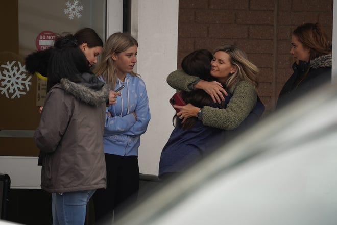 A parent hugs a child as others pick up students from a Meijer store in Oxford following an ongoing shooting situation at Oxford High School in Oxford on November 30, 2021. Police made an arrest one suspect was the shooter and had multiple victims, between four and six, the Oakland County Sheriff's office said.