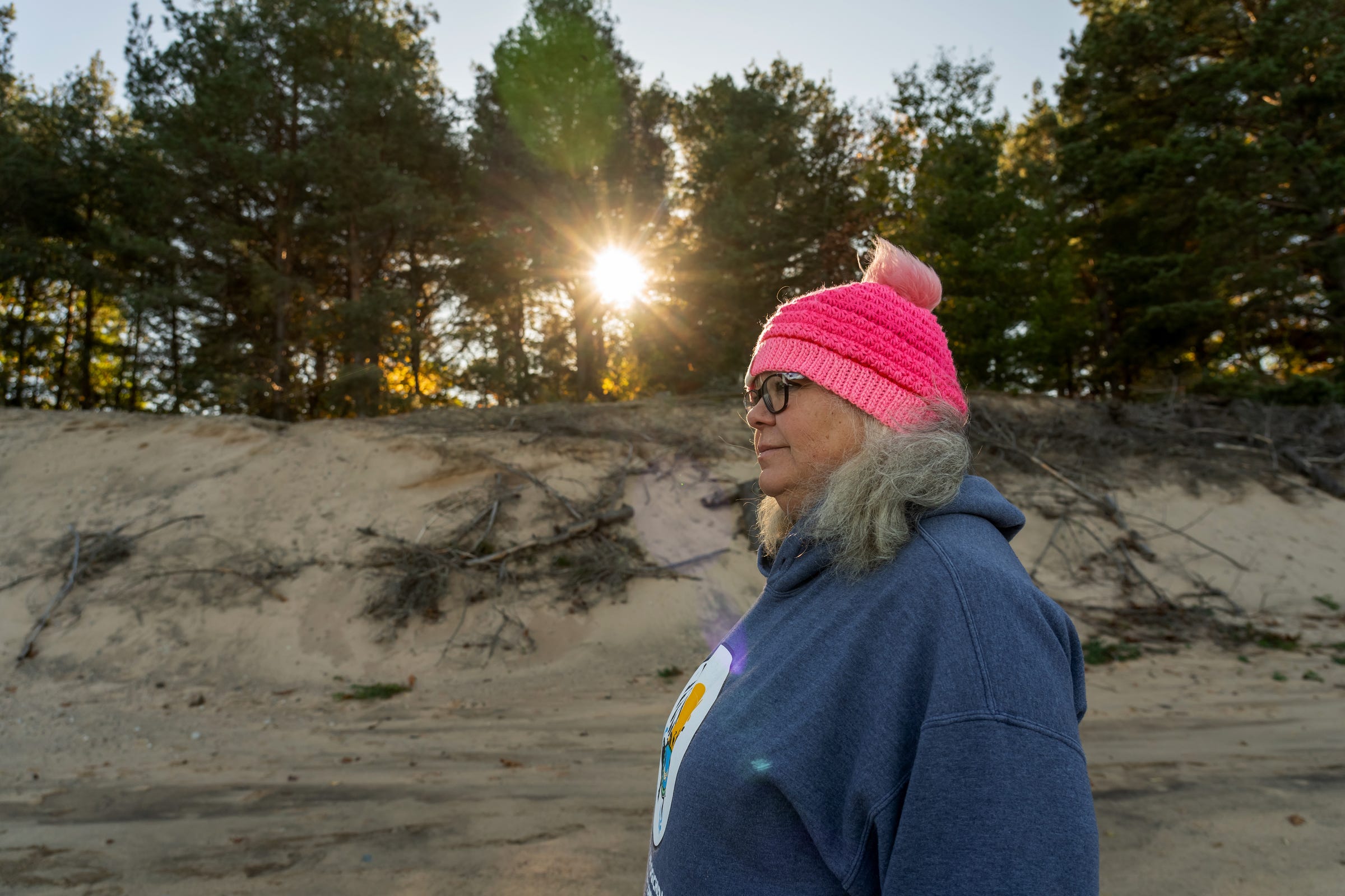 Paula Carrick, the Bay Mills Indian Community's official historian, stands alongside the bluff that marks the collapsing edge of the tribe's Old Indian Burial Ground in Bay Mills Township on Monday, Oct. 18, 2021. “All of this is burial ground,” Carrick said. “This is all caved in since last year. Those trees right here those were on top of the hill before, so that’s all fresh right there.”
