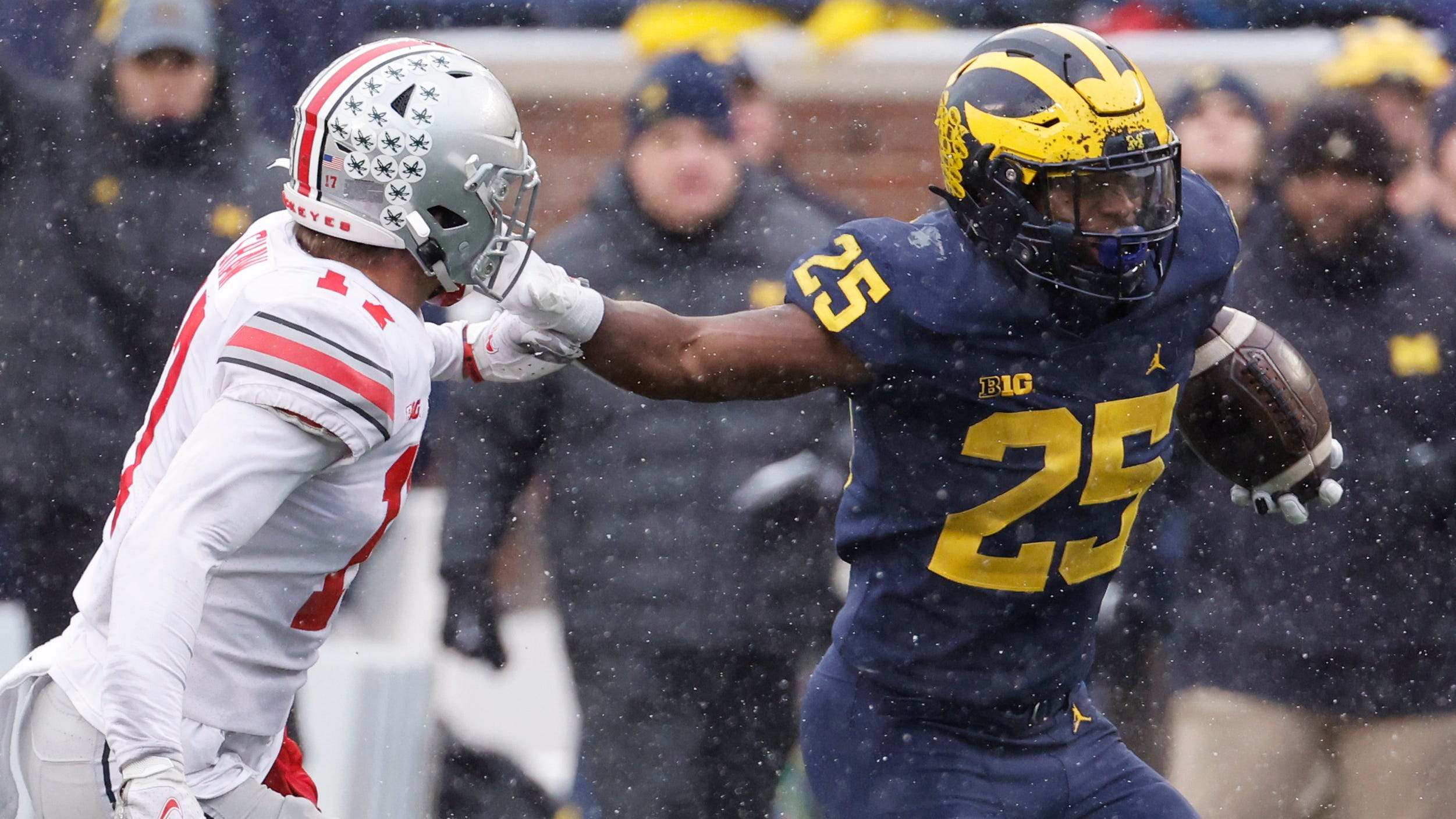 Michigan Wolverines running back Hassan Haskins (25) stiff arms Ohio State Buckeyes safety Bryson Shaw (17) in the second half at Michigan Stadium.