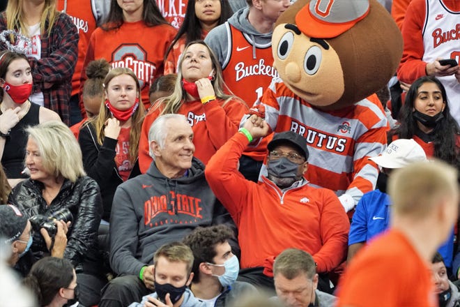 Archie Griffin receives a fist bump from Brutus Buckeye as Jerry Lucas watches.