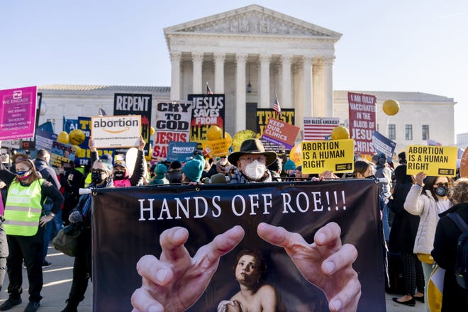 Stephen Parlato of Boulder, Colo., holds a sign that reads "Hands Off Roe!!!" as abortion rights advocates and anti-abortion protesters demonstrate in front of the U.S. Supreme Court, Wednesday in Washington, as the court hears arguments in a case from Mississippi, where a 2018 law would ban abortions after 15 weeks of pregnancy, well before viability.