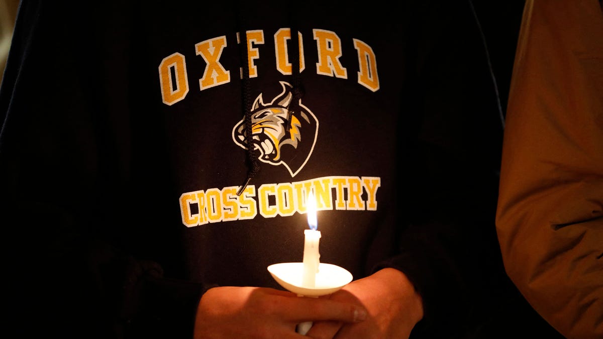 A student holds a candle during a vigil after a shooting at Oxford High School at Lake Pointe Community Church in Lake Orion, Michigan on November 30, 2021.