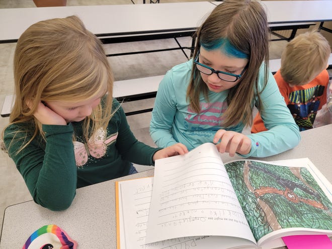 Madalynn Kemp, right, a third grader in Tammy Sorensen's class at Gorrell Elementary School, reads an excerpt from the book "On Our Trip to the Zoo" on Friday to Melody Accetta, a student in Eileen Sirgo's kindergarten class. Sorensen's and Sirgo's classes teamed up to write and illustrate the book.