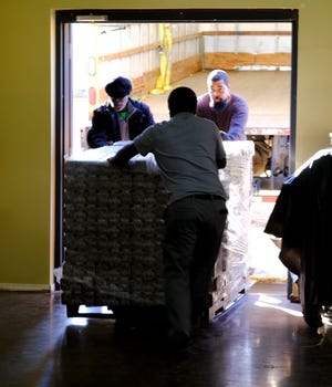 Volunteers unload a pallet of food items. A Table in the Wilderness ministry CEO and president Laurel Mauldin, sits on a pallet of food that Feed The Children gave to the faith-based pantry. Friday, December 3, 2021.