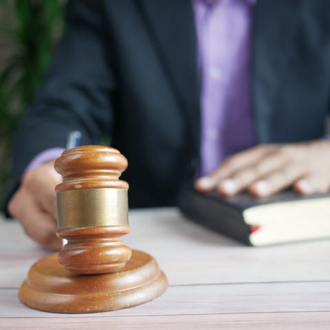 A brown gavel is struck against a sound block in t