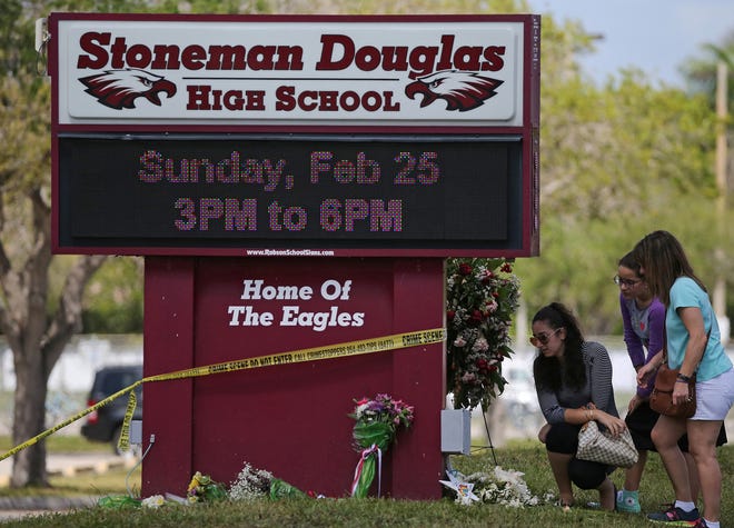 Mourners bring flowers as they pay tribute at a memorial for the victims of the shooting at Marjory Stoneman Douglas High School on Sunday, Feb. 25, 2018 during an open house as parents and students returned to the school for the first time since 17 people were killed in a mass shooting at the school in Parkland on Feb. 14, 2018. (David Santiago/Miami Herald/TNS)