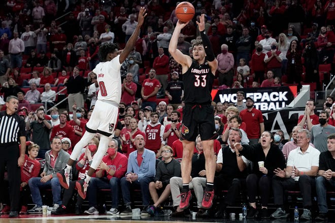 Louisville forward Matt Cross (33) shoots a 3-point basket to take the lead late in the second half while North Carolina State guard Terquavion Smith (0) defends during an NCAA college basketball game in Raleigh, N.C., Saturday, Dec. 4, 2021. (AP Photo/Gerry Broome)