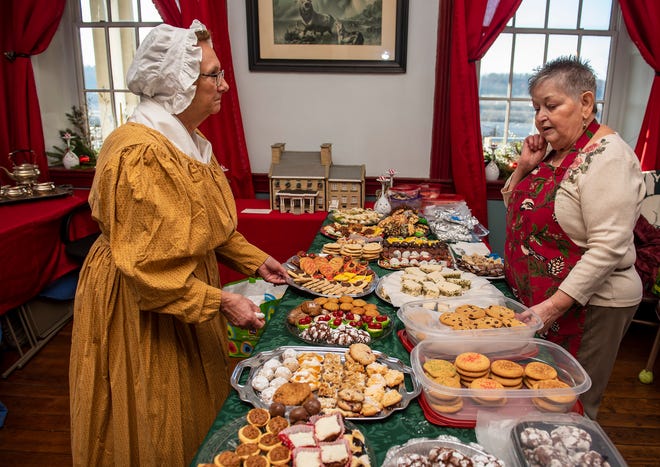 Volunteers Janette Hartley of Economy, left, and Donna Berg of Monaca contemplate where to put more items on the cookie table at the Vicary Mansion Christmas Open House Saturday.
