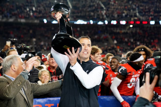 Cincinnati Bearcats head coach Luke Fickell raises the trophy of the American Athletic Conference championship football game, Saturday, Dec. 4, 2021, at Nippert Stadium in Cincinnati. The Cincinnati Bearcats defeated the Houston Cougars, 35-20.