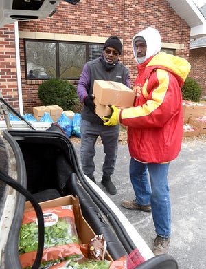 Shawn May, left, and Markus Key, both members of the Progressive Missionary Baptist Church at 702 Banks Ave., load free food baskets into a car’s trunk for two families on Tuesday during the church’s food basket distribution to support families in the community.