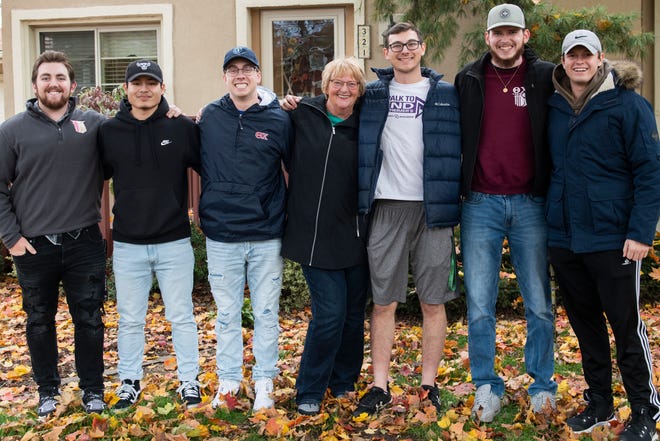 From left, Josh Vaculik, Alex Orr, Cameron Klein, Beverly Reeves, Jack Plumley, Izaac Davis and Aaron Glover pose for a photo outside of Reeves' home in Adrian. Reeve has lived next door to Adrian College's Theta Chi fraternity house for 20 years. She has received a lot of help from the fraternity brothers over the years when it comes to household work and other tasks.