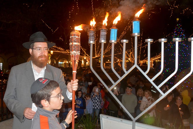 Rabbi Levi Vogel and son Mendel light the Menorah in downtown St. Augustine.