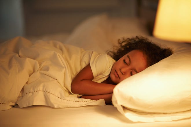 A young girl asleep in a bed. 