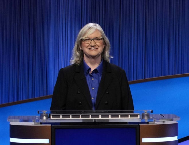 NAU Professor of Elementary Science Education Marti Canipe stands behind a contestant desk on 'Jeopardy!'