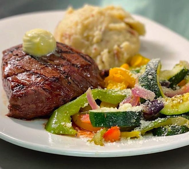 A 10 oz. flat iron steak with red-skinned mashed potatoes and seasonal vegetables is shown at Rainforest Cafe.
