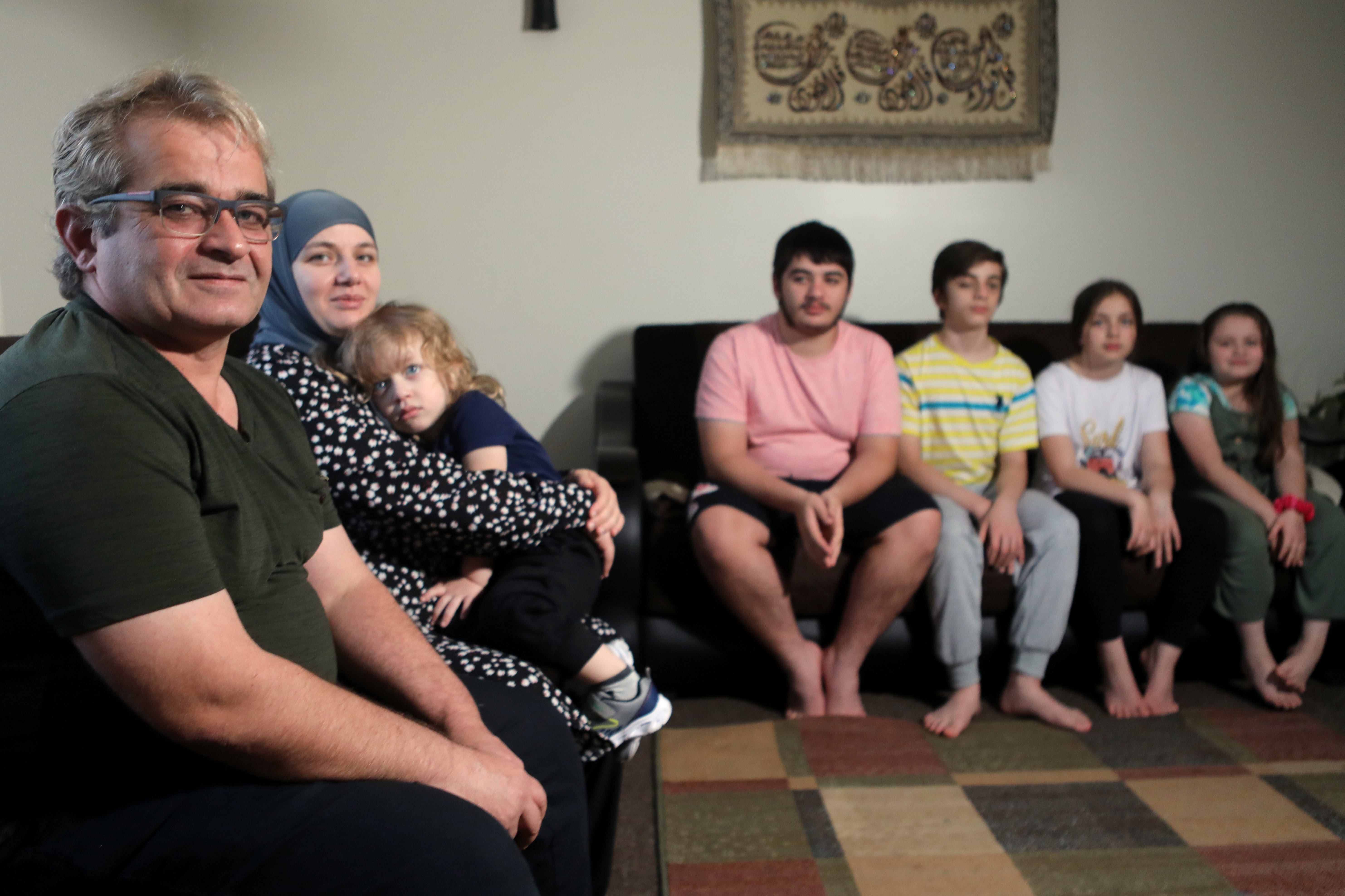 Ayman Isamail and his wife, Hanan Marza, sit with their youngest child, Ellias, 2. Their older children, Mohamad, 17, Adam, 14, Shaimaa, 11, and Rimas, 8, are in the back. The family (before Ellias was born) came to America as Syrian refugees in 2016. Two years later, they moved into this apartment in Haledon. Wednesday, Nov. 10, 2021.