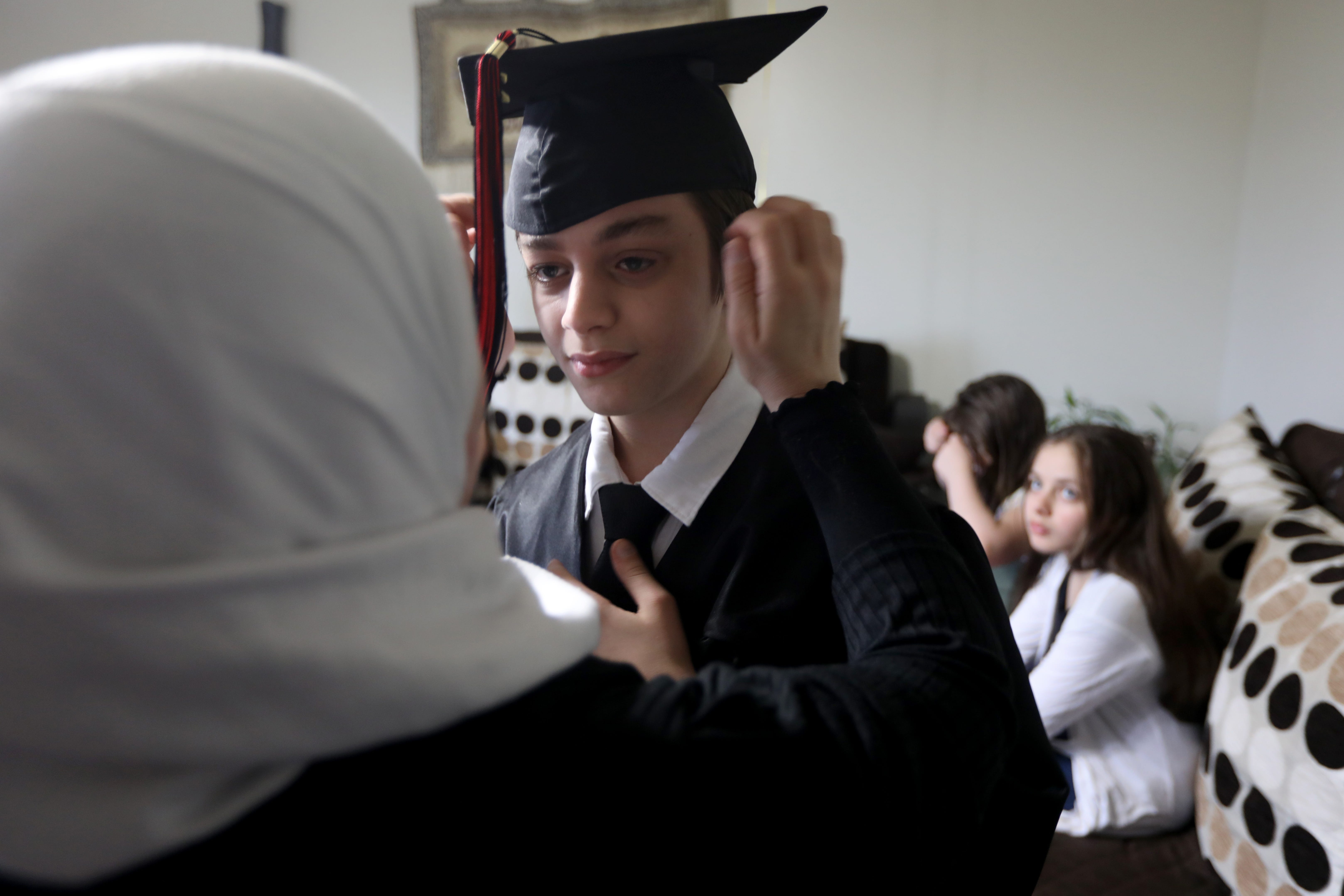 Hanan Marza helps her son Adam Ismail with his cap and  gown before eighth grade graduation June 22, 2021.