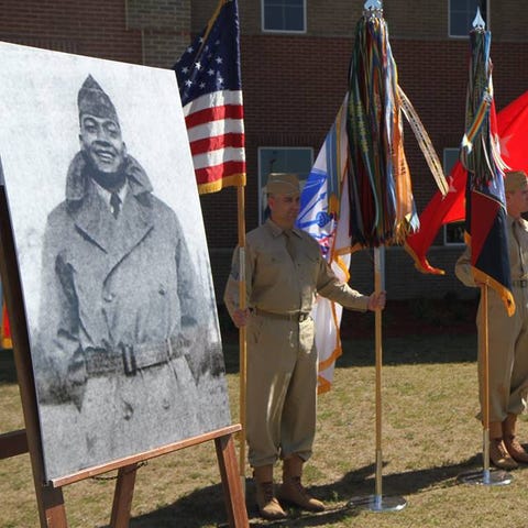 Soldiers hold flags next to a picture of Pfc. Char