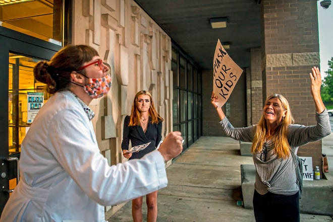 Dr. Brooke Decker, left, of Marshall, argues with Dana Gibson, right, of McCandless, about opposition to a mask mandate for students while Everlee Craddock, of Baden, looks on, Aug. 25, 2021, at at North Allegheny Senior High School in McCandless, Pa. The legality of an order by Pennsylvaniaâ€™s acting state Health secretary requiring masks in K-12 schools and child care facilities is before the Pennsylvania Supreme Court. The two sides are set to argue their respective positions before the justices on Wednesday, Dec. 8, 2021 in Philadelphia.(Alexandra Wimley/Pittsburgh Post-Gazette via AP)