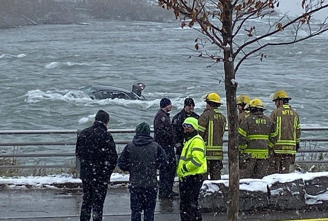 First responders monitor a car partially submerged in the Niagara River near the brink of American Falls, Wednesday, Dec. 8, 2021, in Niagara Falls, N.Y.