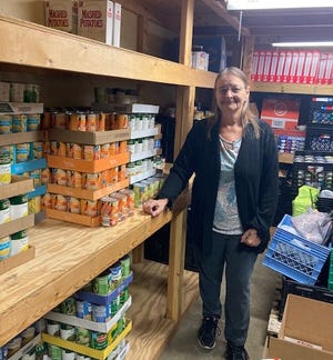 Gina Bichard, director of the food pantry at The Salvation Army in Cambridge, stands among the supplies used to feed local residents in need. The agency fed more than 7,000 people in 2020, but that total has fallen to less than 5,000 this year.