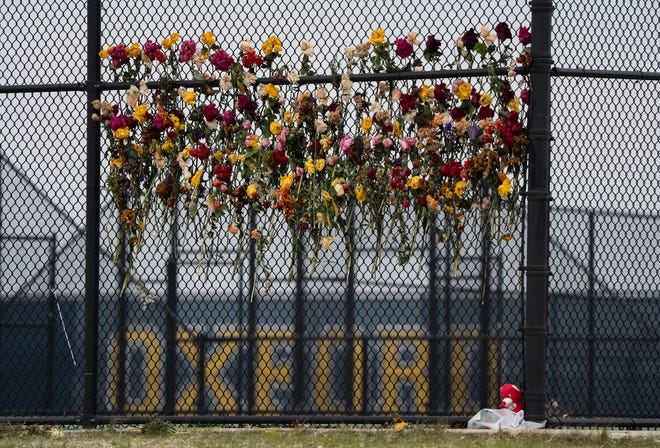 Flowers are attached to the fence outside of the tennis courts at Oxford High School on Thursday, December 9, 2021, as a memorial in memory of the four students shot and killed and multiple others after a classmate opened fire during an active shooter at Oxford High School.