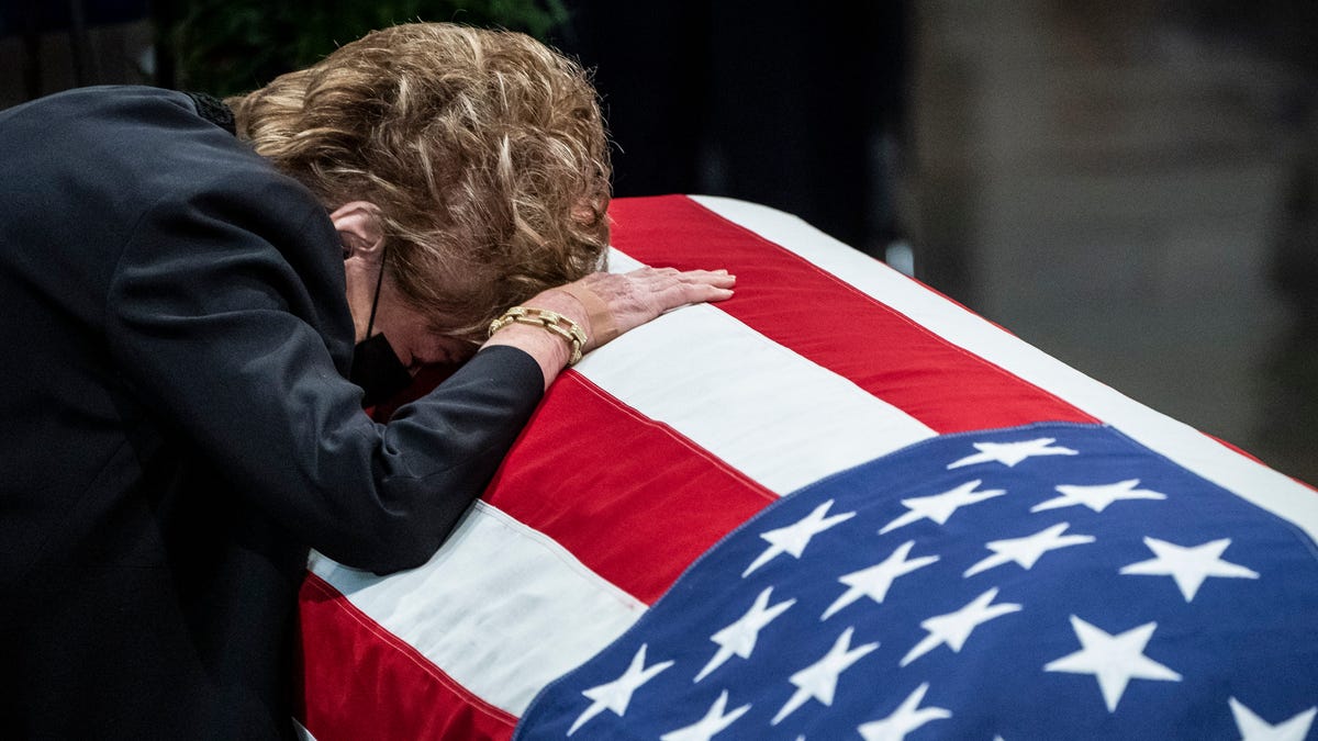 Former Sen. Elizabeth Dole, rests her head on the casket of her husband, former Sen. Bob Dole of Kansas, as he lies in state in the Rotunda of the U.S. Capitol, Thursday, Dec. 9, 2021 in Washington.