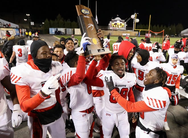 Aliquippa players celebrate with the championship trophy after defeating Bishop McDevitt 34-27 in the PIAA Class 4A championship football game, Dec. 9, 2021, at HersheyPark Stadium in Hershey. 